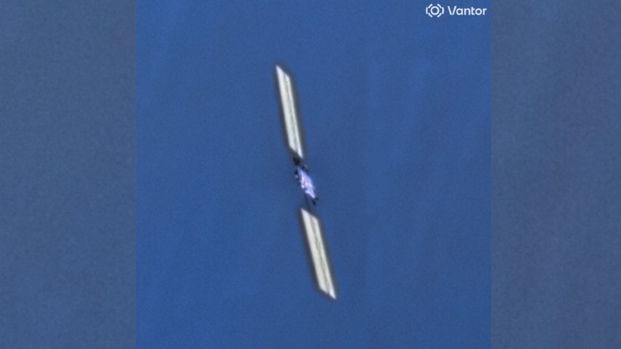 closeup photo taken from space of a boxy satellite with long, rectangular solar arrays extending on either side of its body