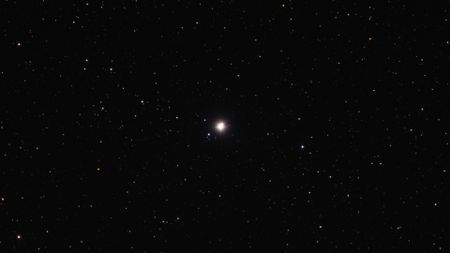 A bright dot of a star in the darkness of space with stars all around.